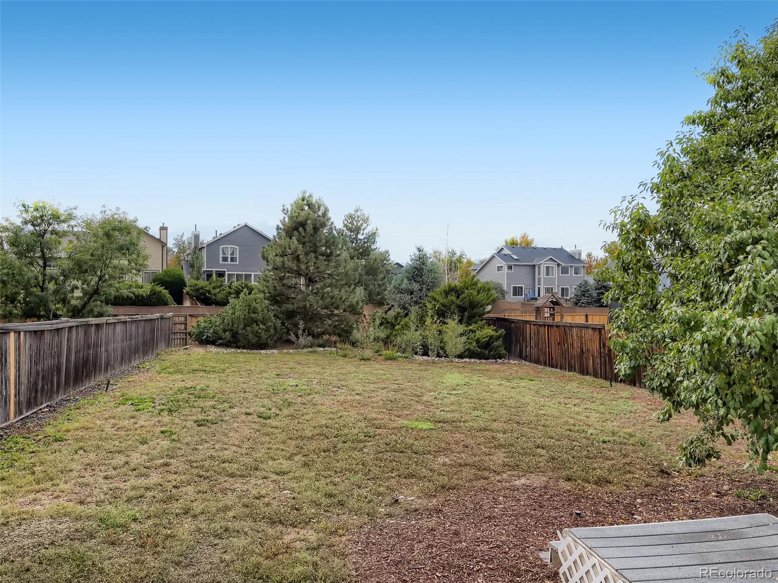 9760 South Castle Ridge Circle Highlands Ranch, CO 80129 - Photo 21 of 25 a view of a yard with a house and trees in the background