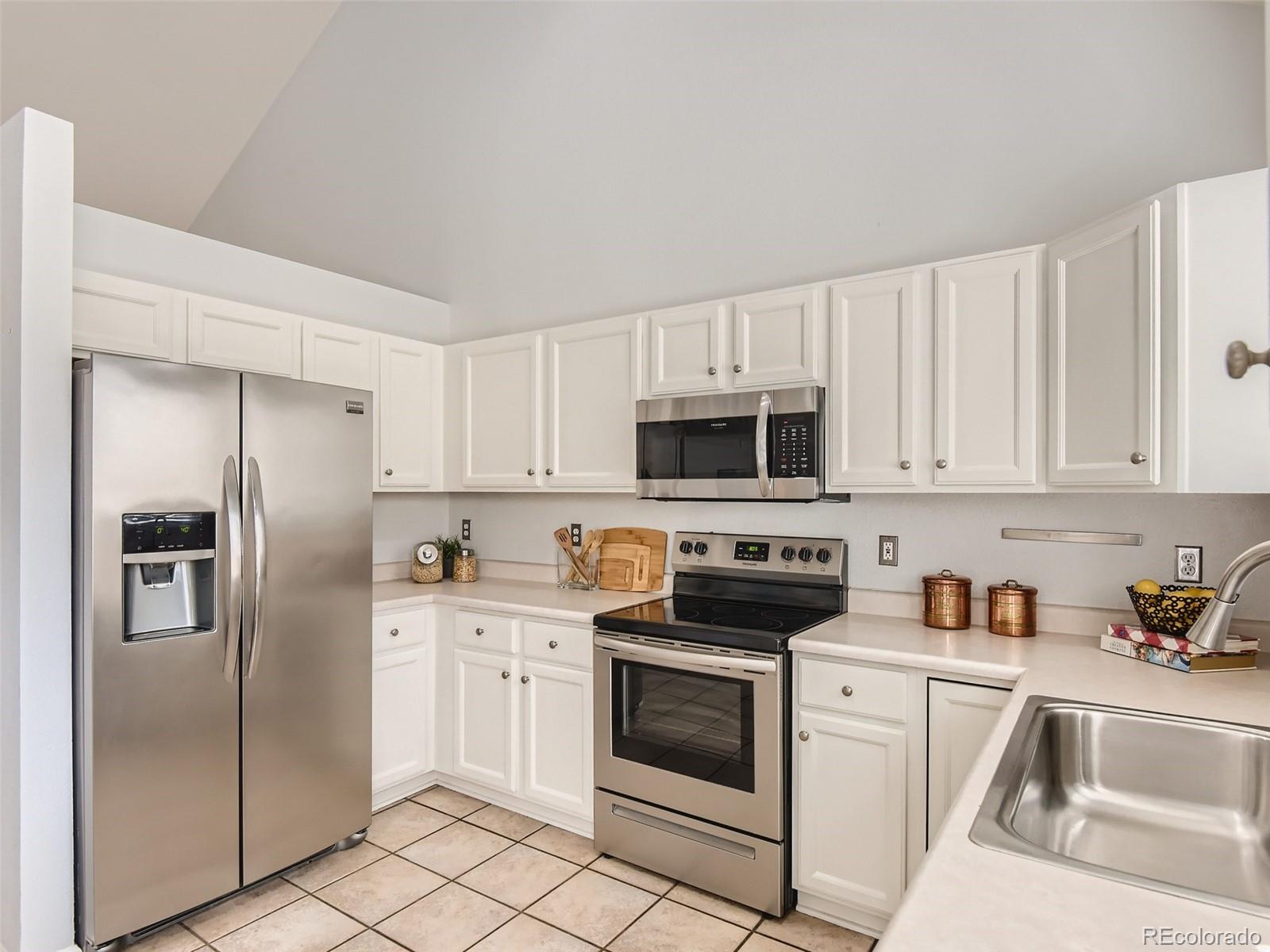 9760 South Castle Ridge Circle Highlands Ranch, CO 80129 - Photo 6 of 25 a kitchen with white cabinets stainless steel appliances and a sink