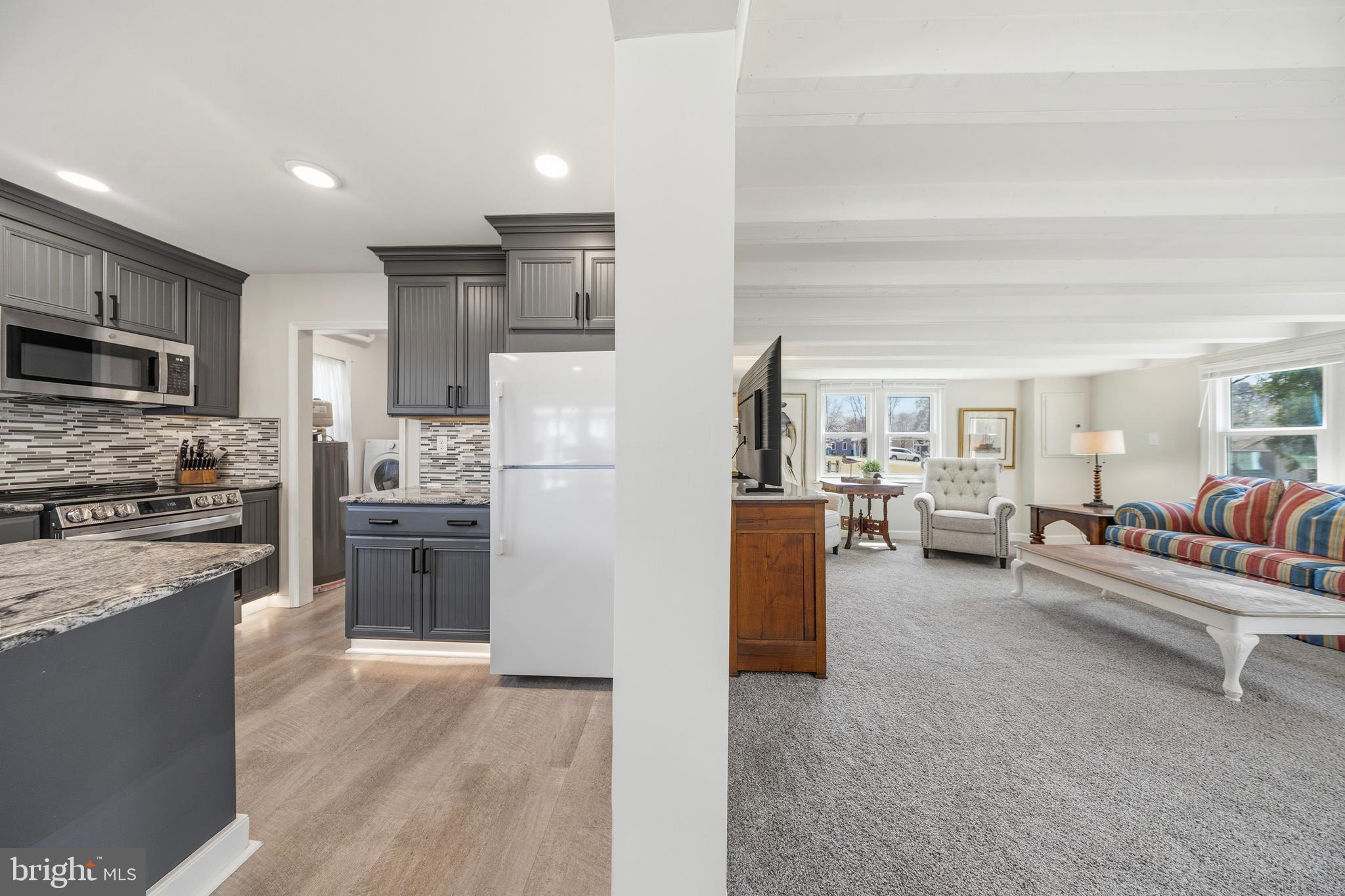 20826 Bivalve Wharf Road Bivalve, MD 21865 - Photo 17 of 52 a kitchen with stainless steel appliances kitchen island granite countertop a refrigerator oven a sink dishwasher a dining table and chairs with wooden floor