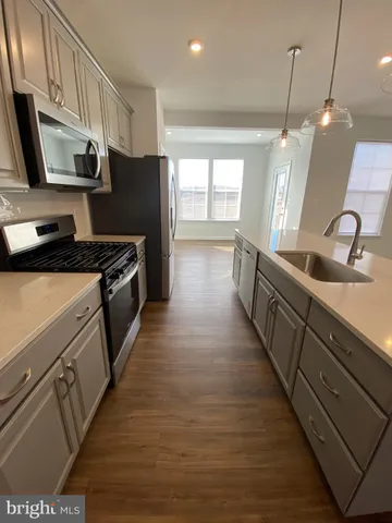 a kitchen with granite countertop a sink a counter top space stainless steel appliances and cabinets