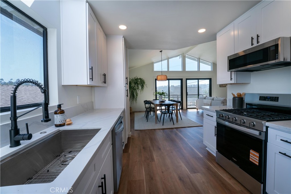 675 Huntington Road Cambria, CA 93428 - Photo 10 of 30 a kitchen with stainless steel appliances granite countertop a stove top oven a sink dishwasher a dining table and chairs with wooden floor