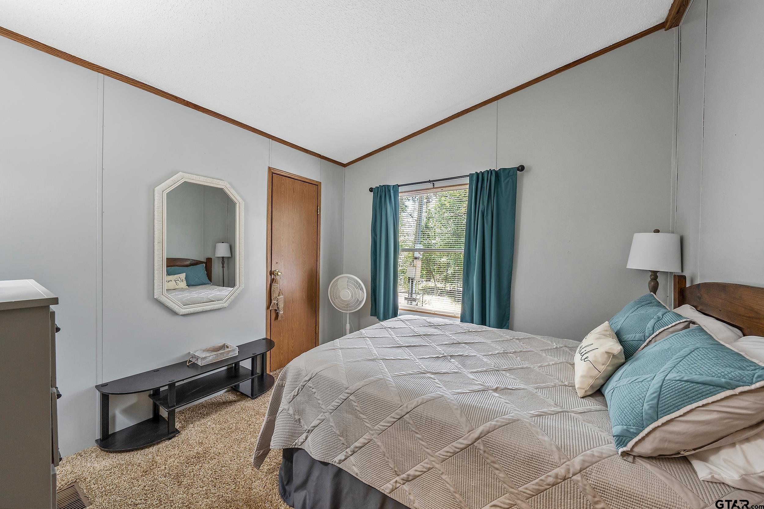 749 County Road 3420 Hawkins, TX 75765 - Photo 18 of 29 a bedroom with a bed a mirror and lamp