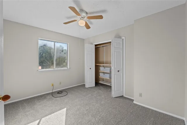 an empty room with a window and a ceiling fan