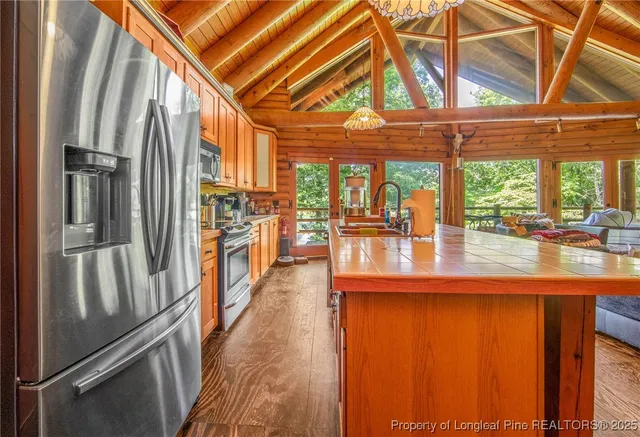 a kitchen with stainless steel appliances granite countertop a refrigerator and a view of living room