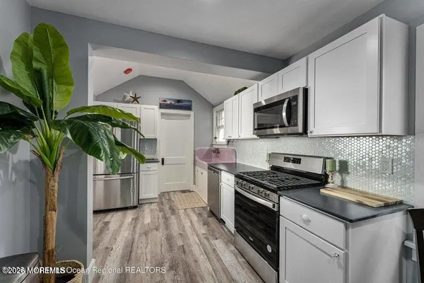 a kitchen with granite countertop a sink stove and microwave