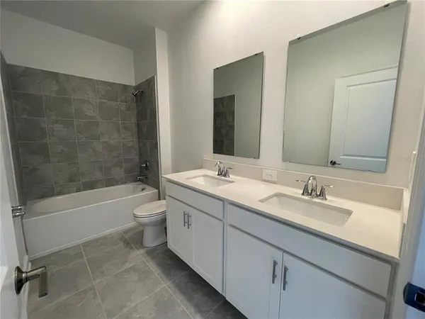 a bathroom with a double vanity sink toilet mirror and bathtub