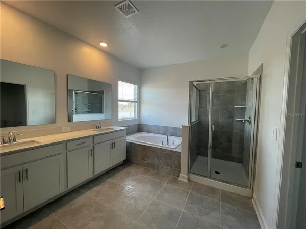 a spacious bathroom with a mirror a shower and a sink