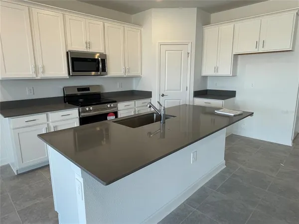 a kitchen with stainless steel appliances granite countertop a sink a stove top oven a granite counter tops and white cabinets