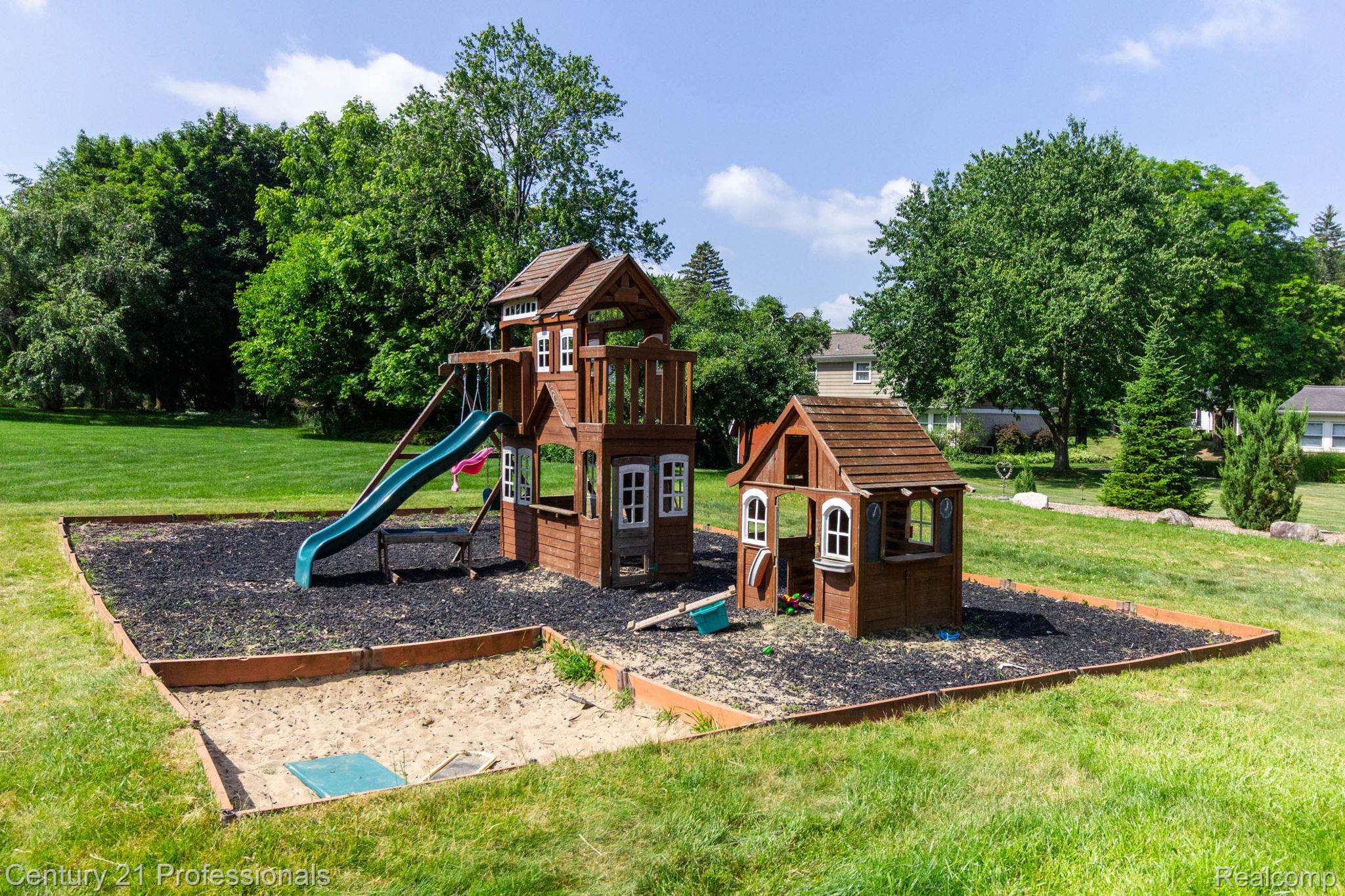 671 Bridgestone Drive Rochester, MI 48309 - Photo 45 of 50 Outdoor play area featuring a multi-level wooden playset with a slide, a separate playhouse, and an integrated sandpit
