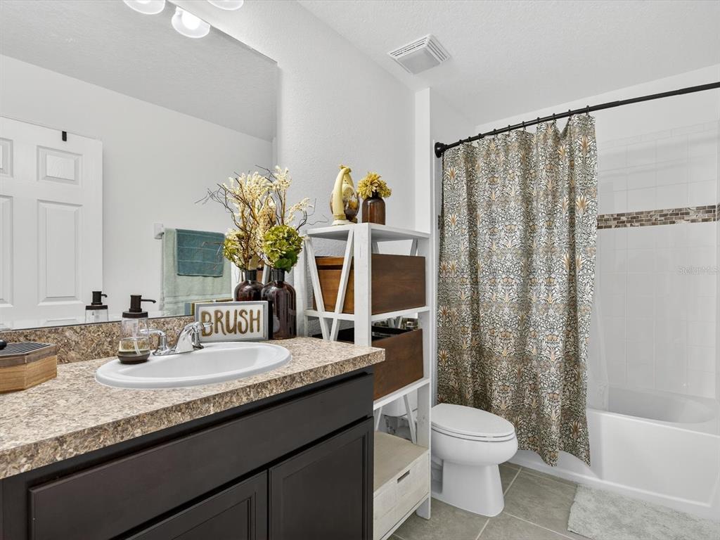 439 Annabelle Way Davenport, FL 33837 - Photo 20 of 31 a bathroom with a granite countertop sink a toilet and shower curtain