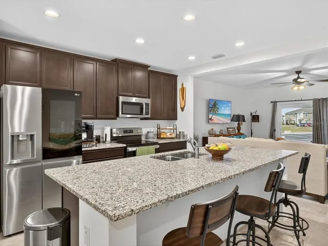 a kitchen with a stove a kitchen island a sink cabinets and stainless steel appliances