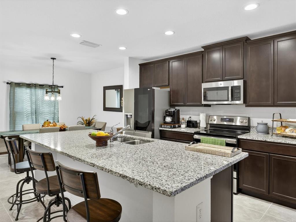 439 Annabelle Way Davenport, FL 33837 - Photo 9 of 31 a kitchen with sink a refrigerator and chairs