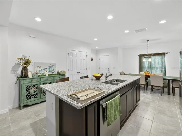 a view of kitchen island with granite countertop a sink a center island and some chairs