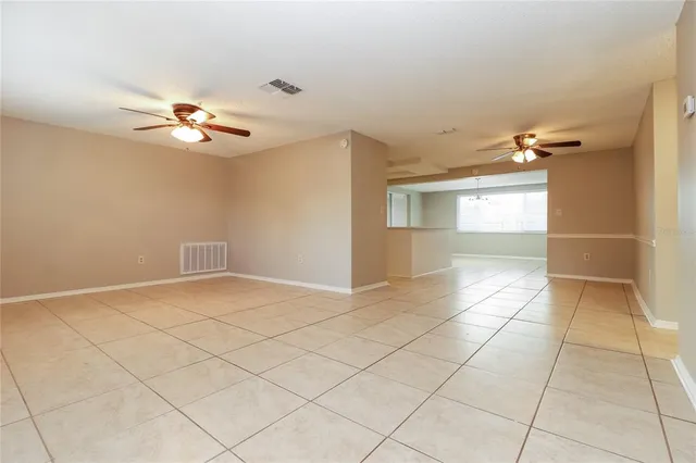 a view of an empty room and a bathroom with a chandelier fan