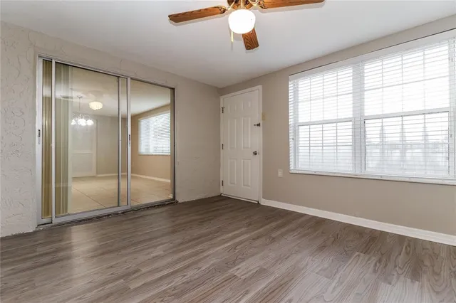 an empty room with wooden floor and windows