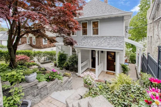 a front view of a house with a yard and potted plants
