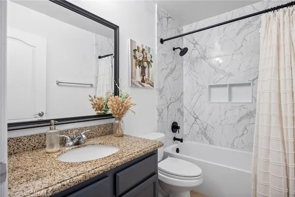 a bathroom with a granite countertop sink a toilet and a mirror