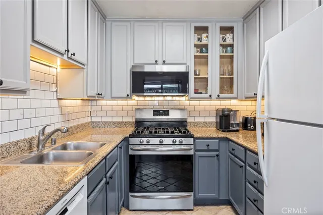 a kitchen with granite countertop a sink stainless steel appliances and cabinets