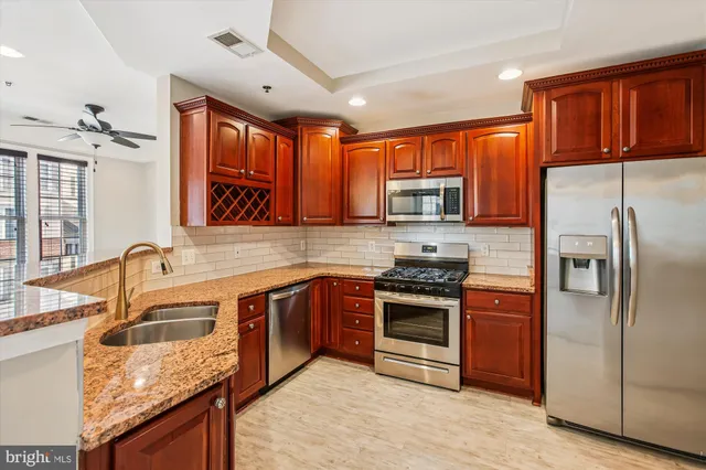 a kitchen with stainless steel appliances granite countertop a sink stove and refrigerator