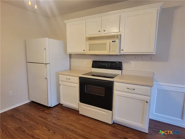 a kitchen with white cabinets white stainless steel appliances and wooden floors