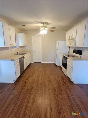 a kitchen with granite countertop a stove top oven a sink dishwasher and a refrigerator with wooden floor