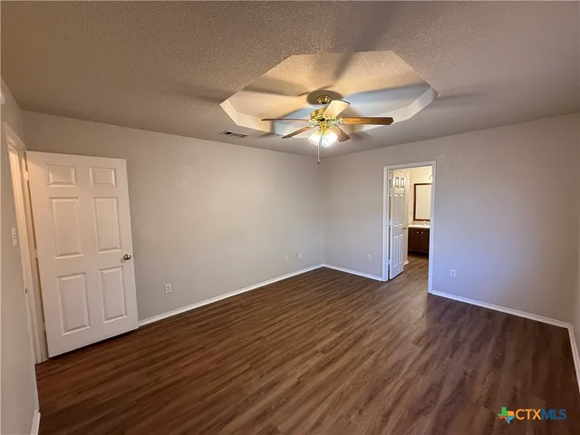 an empty room with wooden floor fan and windows