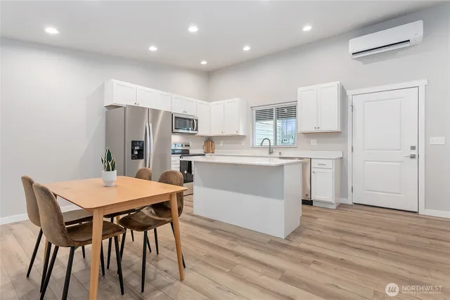 a kitchen with stainless steel appliances a white table chairs and a refrigerator