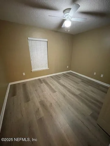 an empty room with a ceiling fan and window