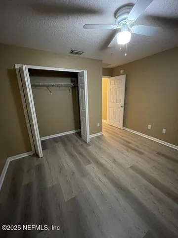 an empty room with wooden floor fan and windows
