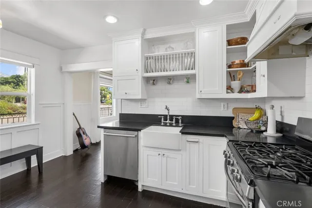 a kitchen with granite countertop a sink a stove and wooden floor