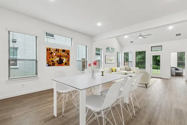a living room with furniture a dining table and wooden floor next to a window