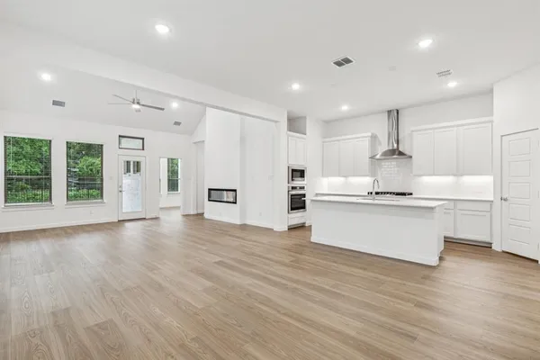 a view of kitchen with granite countertop refrigerator oven sink and white cabinets with wooden floor