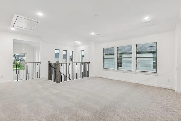 a view of an empty room with wooden floor and windows