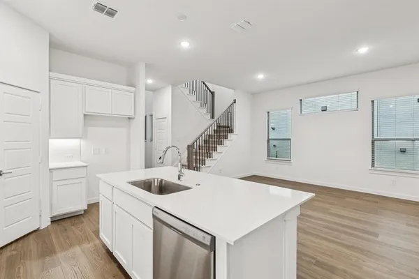 a kitchen with a sink a refrigerator and white cabinets