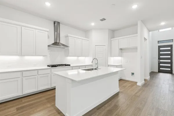 a kitchen with stainless steel appliances granite countertop a sink stove and white cabinets with wooden floor