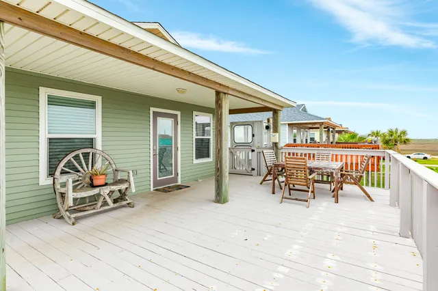 a view of roof deck with table and chairs a barbeque with wooden floor and fence