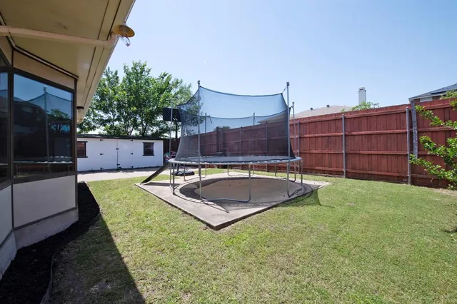 a view of a backyard with couches plants and wooden fence