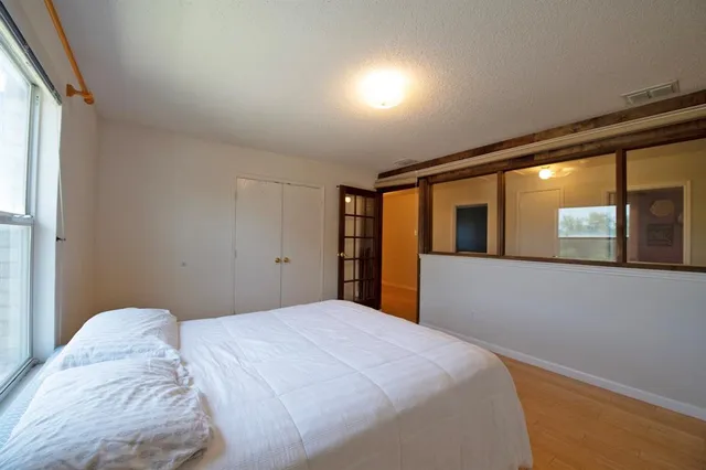 a view of a hallway with wooden floor and a bathroom