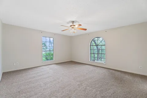 an empty room with windows and ceiling fan