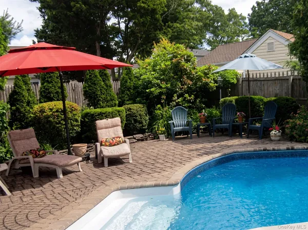 a view of a backyard with table and chairs potted plants and large tree