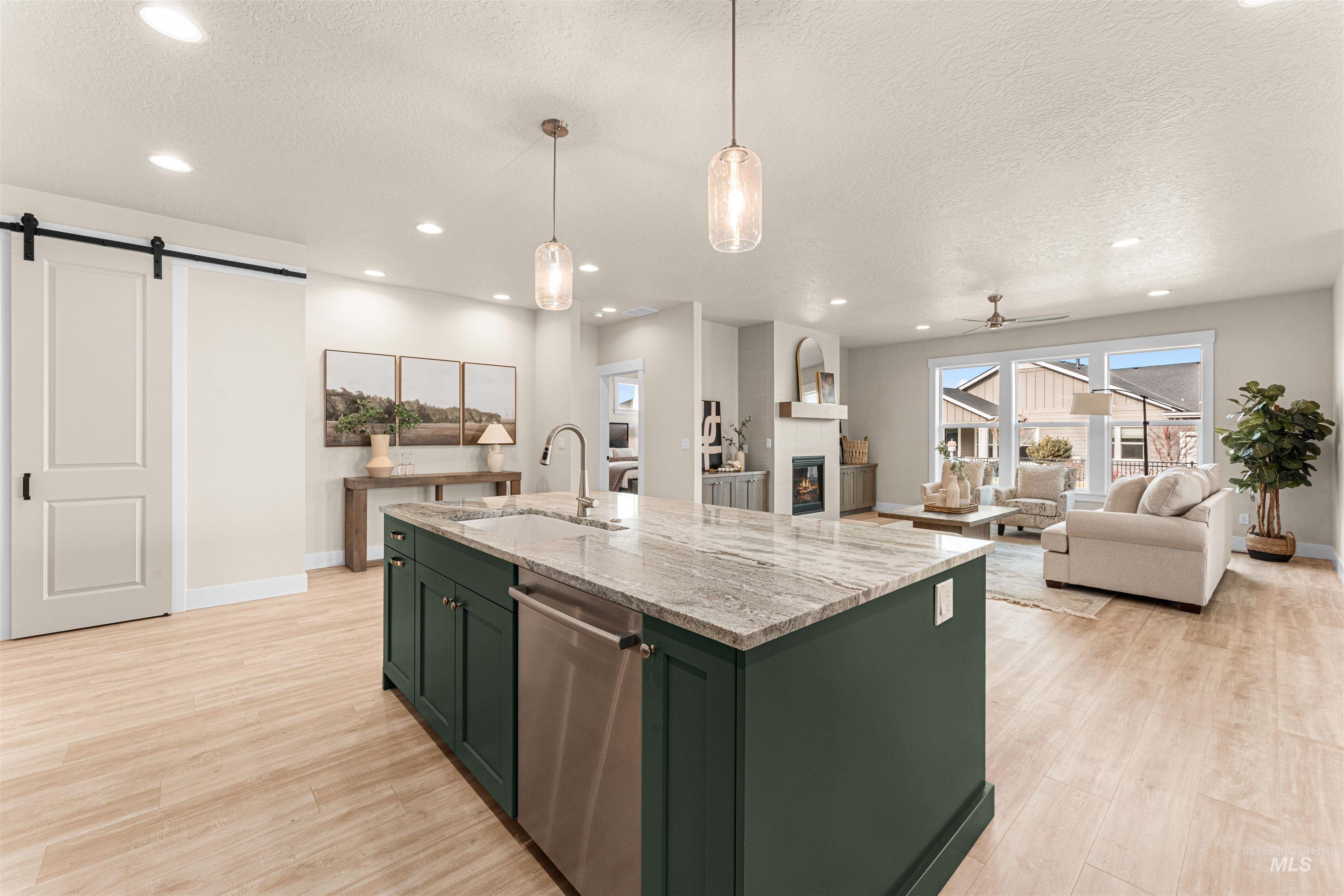 8082 Tandy Cv Street Middleton, ID 83644 - Photo 37 of 37 Kitchen featuring green cabinets, a barn door, a ceiling fan, light stone countertops, and open floor plan