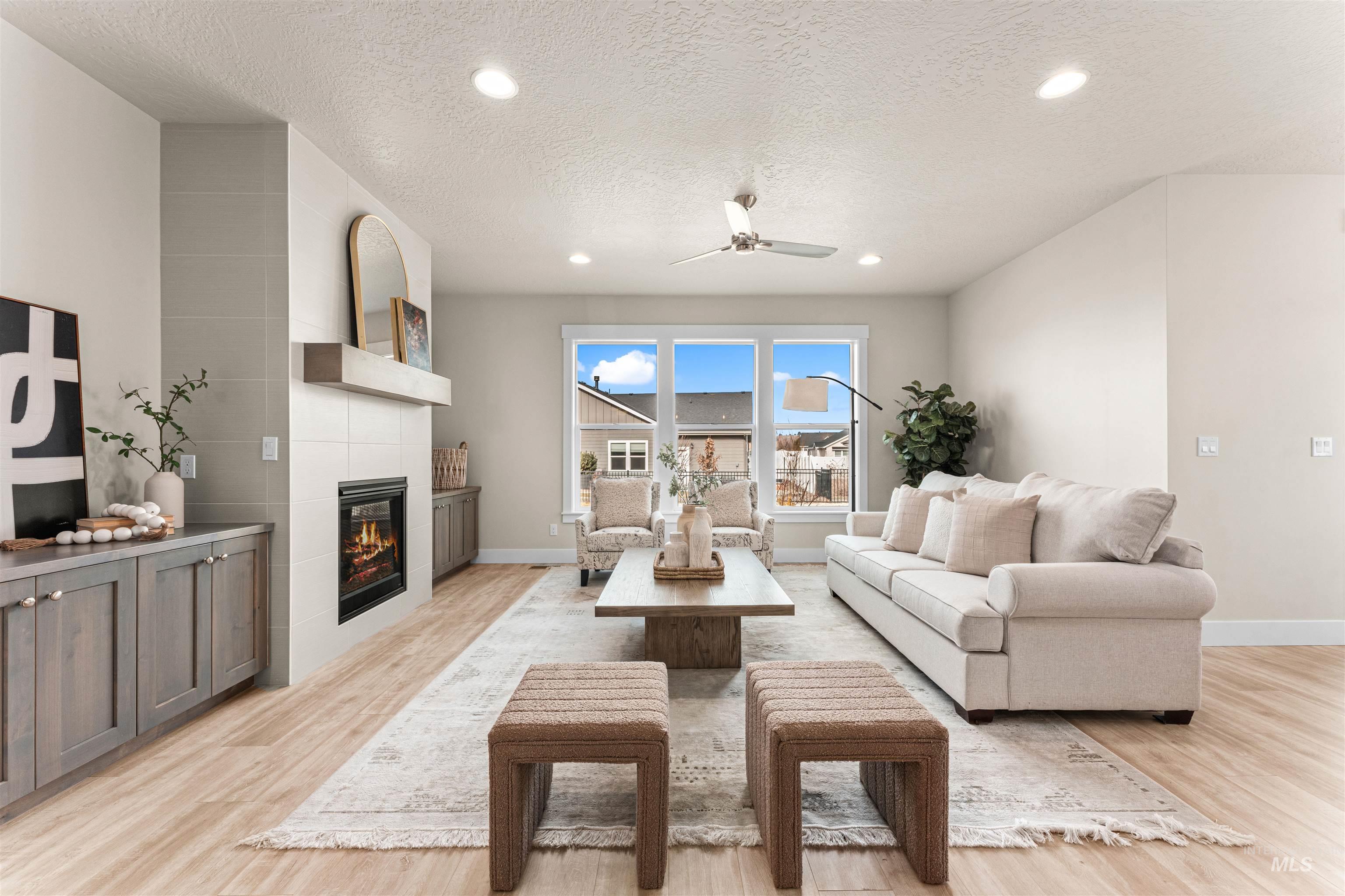 8082 Tandy Cv Street Middleton, ID 83644 - Photo 3 of 37 Living room featuring light wood-type flooring, ceiling fan, a tiled fireplace, a textured ceiling, and recessed lighting