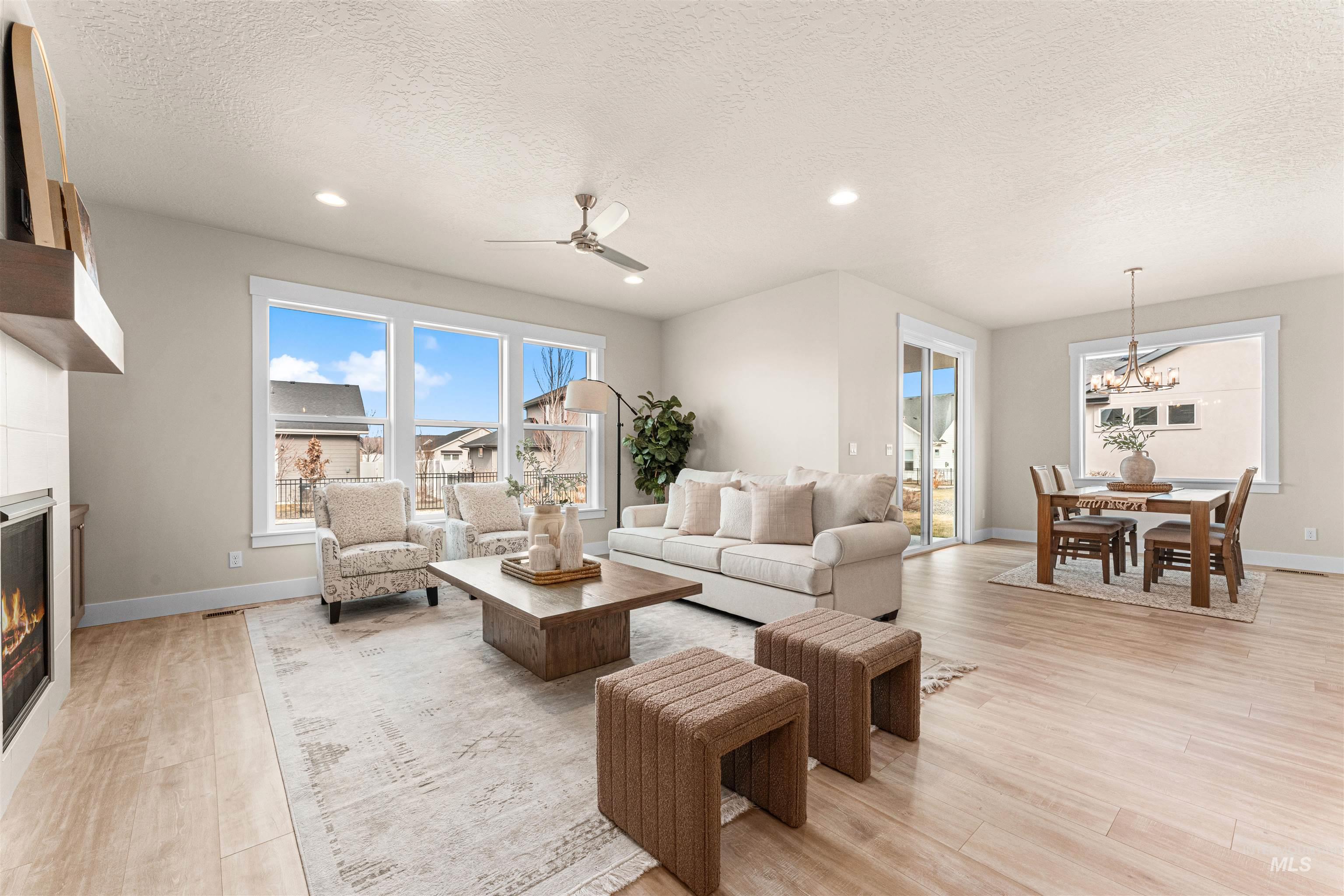 8082 Tandy Cv Street Middleton, ID 83644 - Photo 5 of 37 Living room featuring light wood-style floors, a ceiling fan, a large fireplace, a textured ceiling, and healthy amount of natural light
