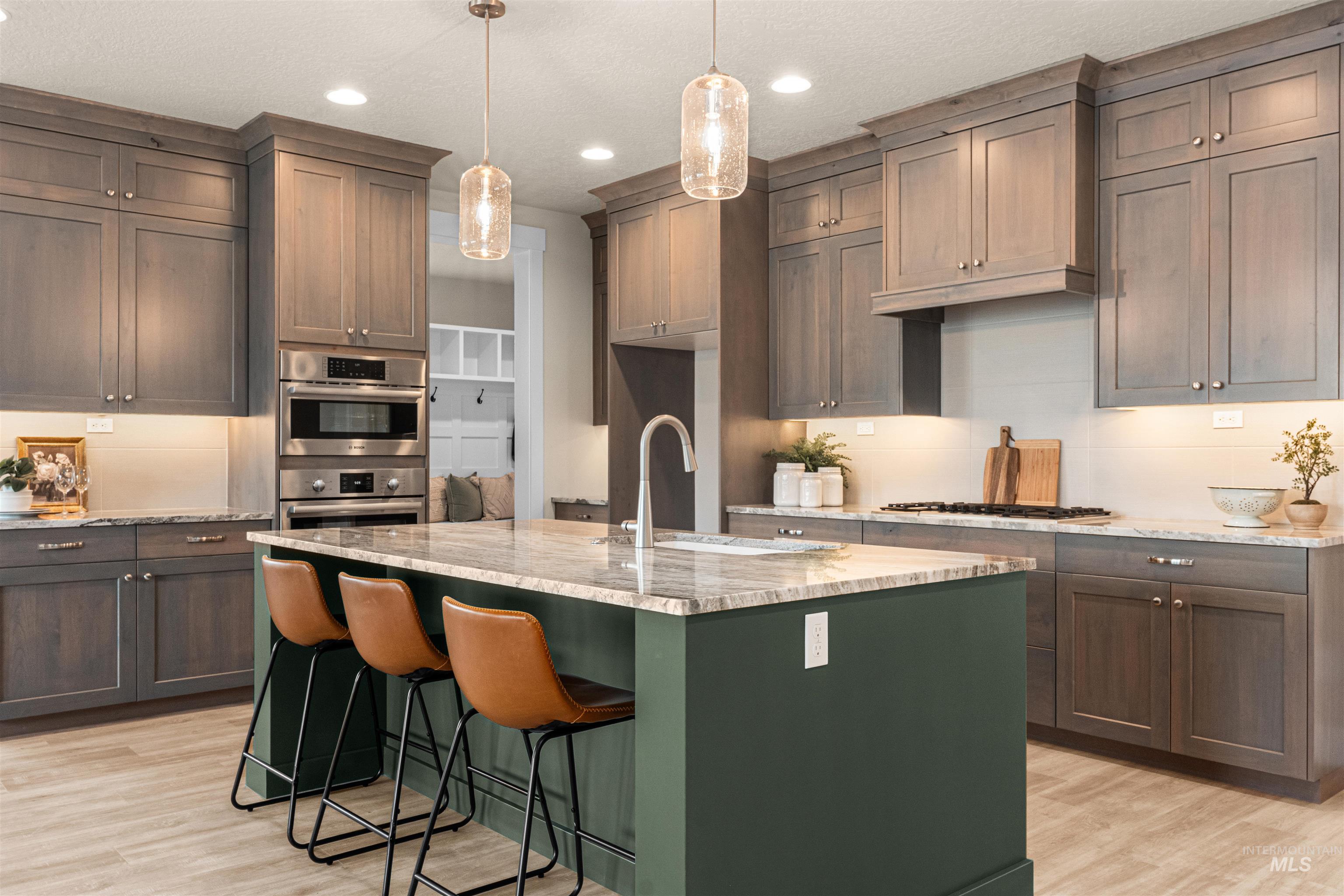 8082 Tandy Cv Street Middleton, ID 83644 - Photo 7 of 37 Kitchen with light stone countertops, light wood-style floors, a kitchen breakfast bar, a kitchen island with sink, and decorative light fixtures