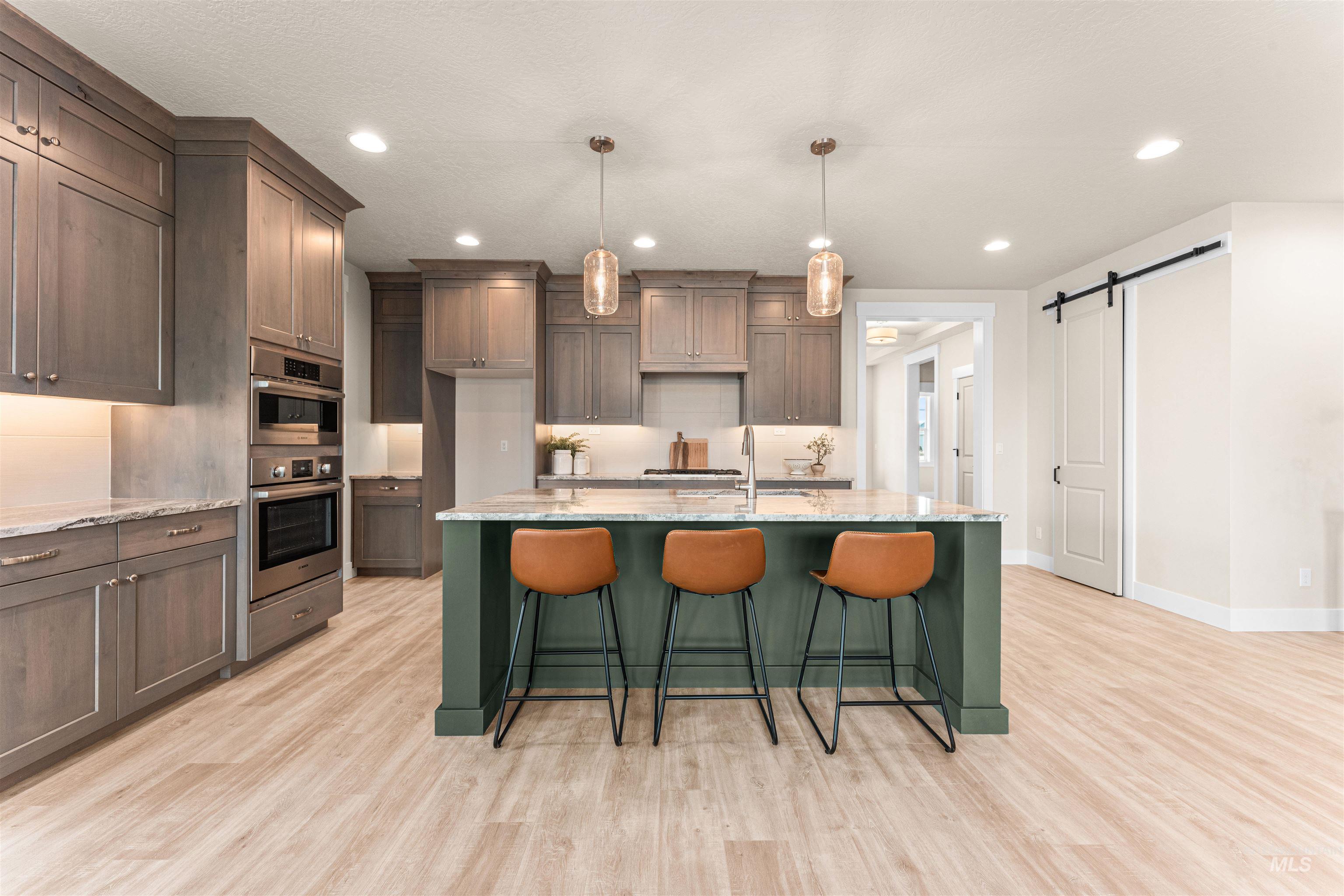 8082 Tandy Cv Street Middleton, ID 83644 - Photo 8 of 37 Kitchen with a barn door, light stone counters, a breakfast bar, light wood-style floors, and pendant lighting
