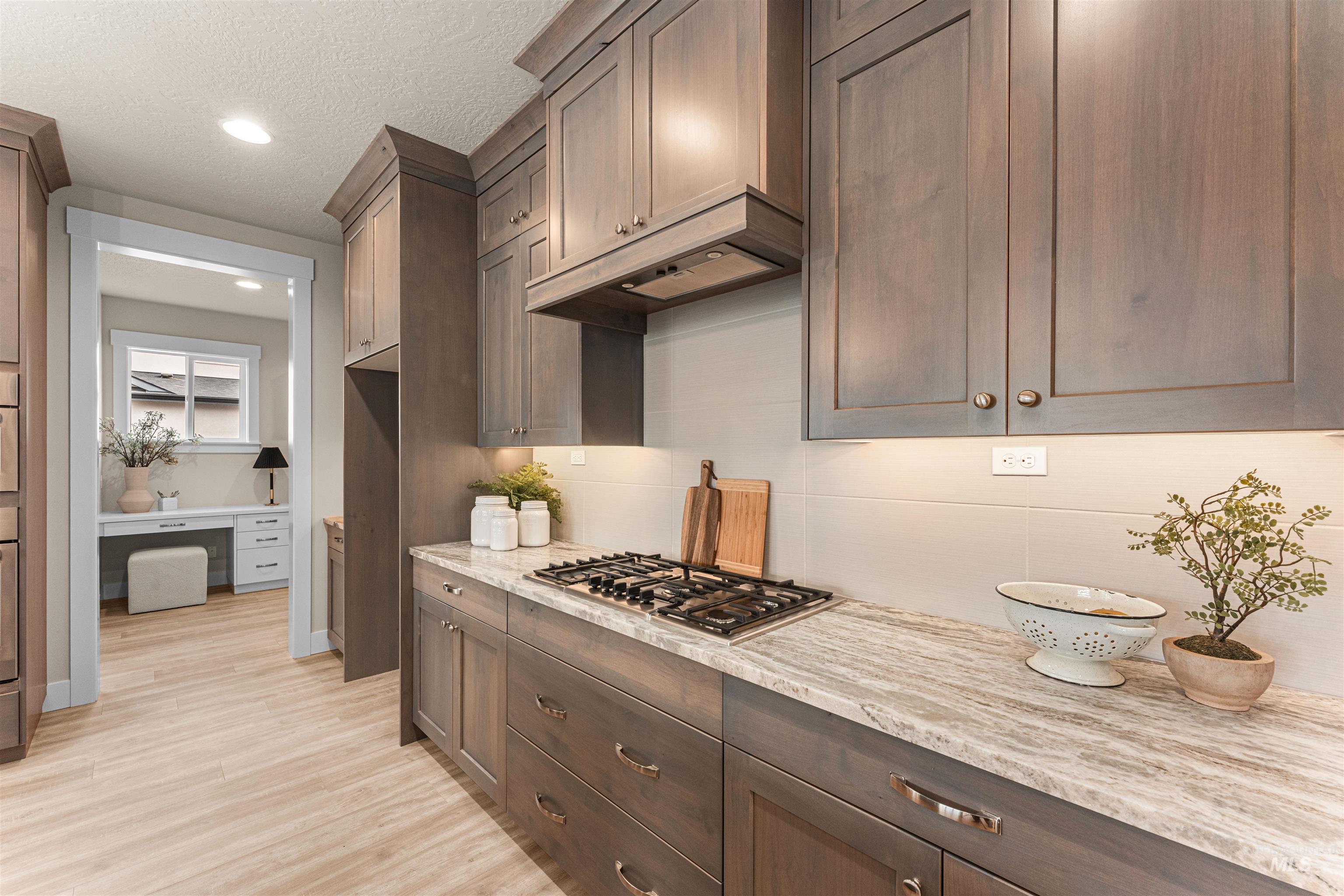 8082 Tandy Cv Street Middleton, ID 83644 - Photo 9 of 37 Kitchen featuring light stone counters, light wood-style floors, stainless steel gas cooktop, recessed lighting, and a textured ceiling