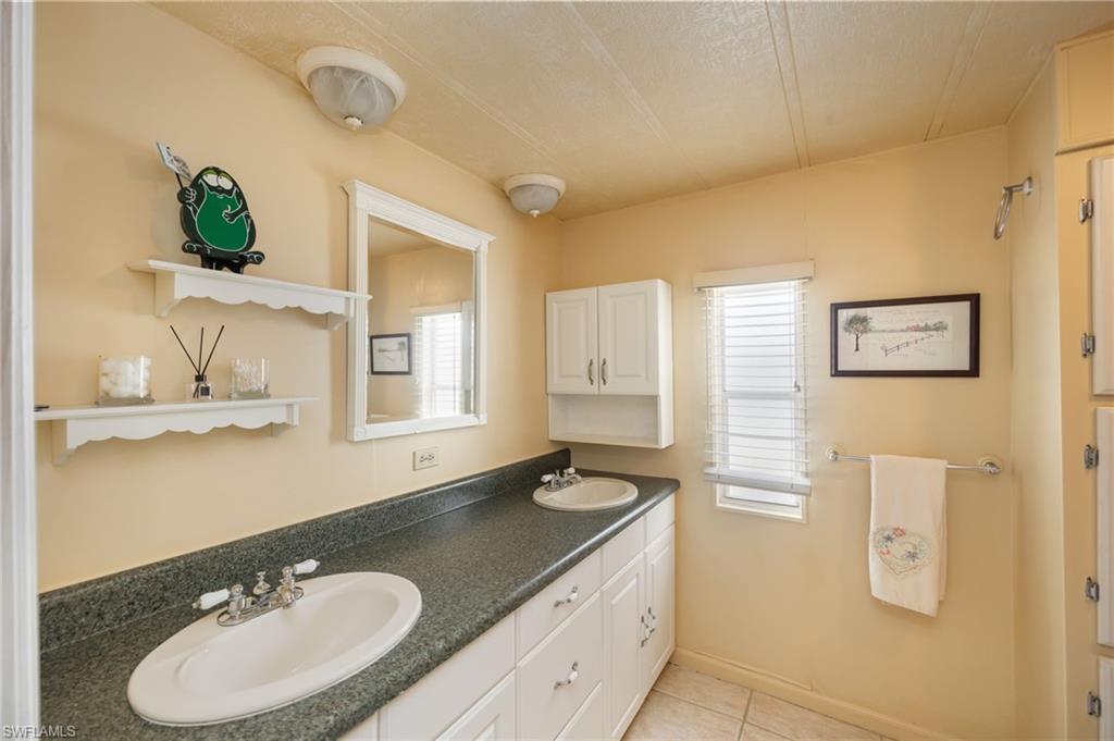21 San Lu Rue Avenue, Unit 21 Naples, FL 34104 - Photo 13 of 33 a bathroom with a granite countertop sink and a mirror