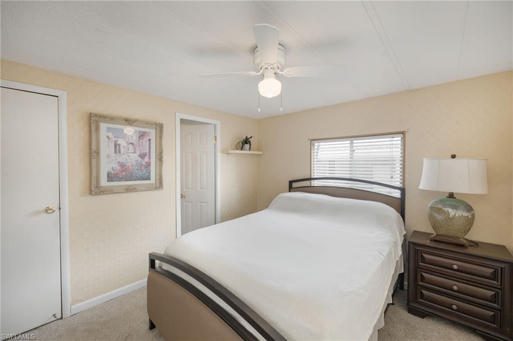 21 San Lu Rue Avenue, Unit 21 Naples, FL 34104 - Photo 15 of 33 a bedroom with a bed and a chandelier