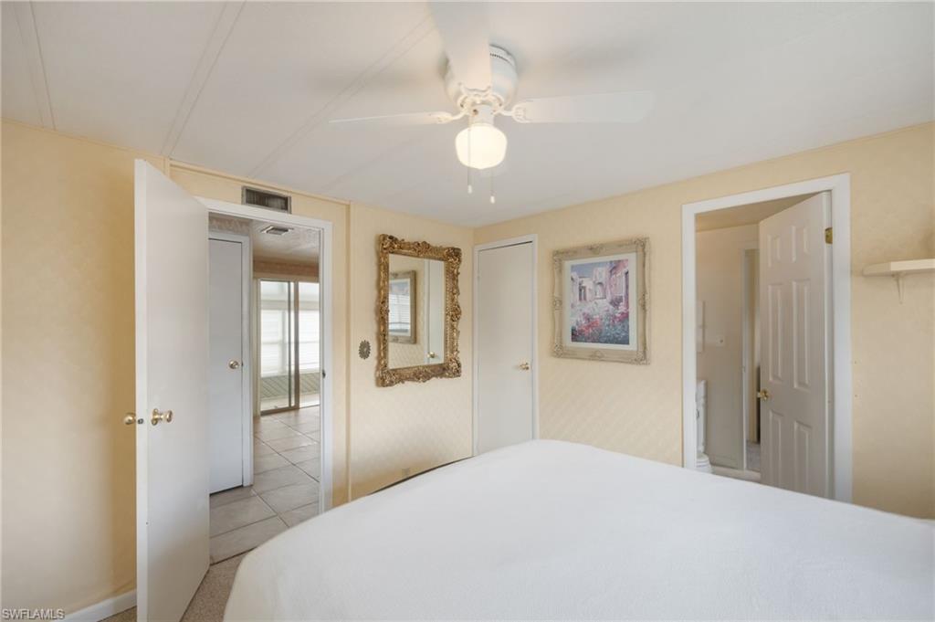21 San Lu Rue Avenue, Unit 21 Naples, FL 34104 - Photo 16 of 33 a bedroom with a bed and a chandelier