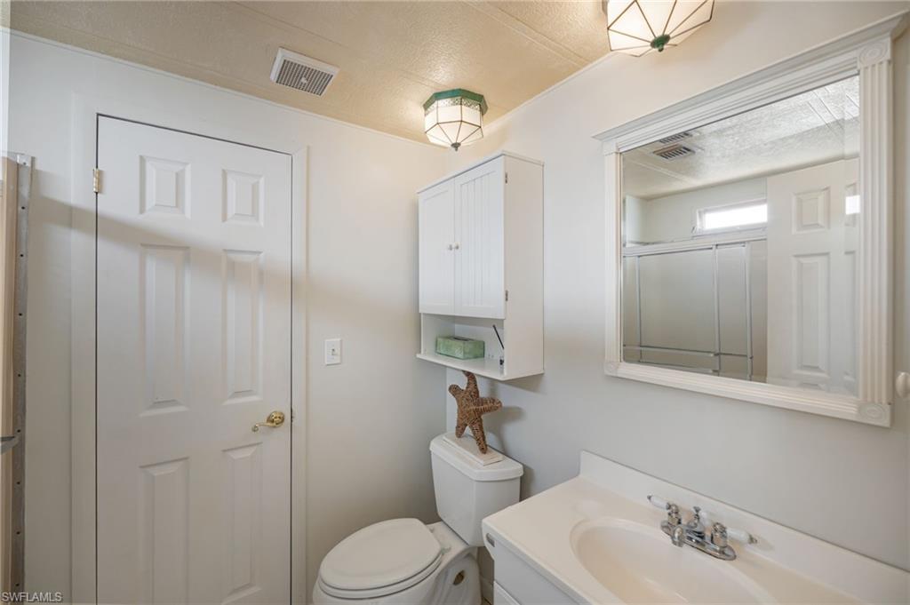 21 San Lu Rue Avenue, Unit 21 Naples, FL 34104 - Photo 18 of 33 a bathroom with a sink a toilet and a mirror